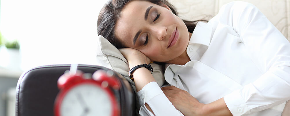 Mujer sobre una almohada durmiendo con un reloj