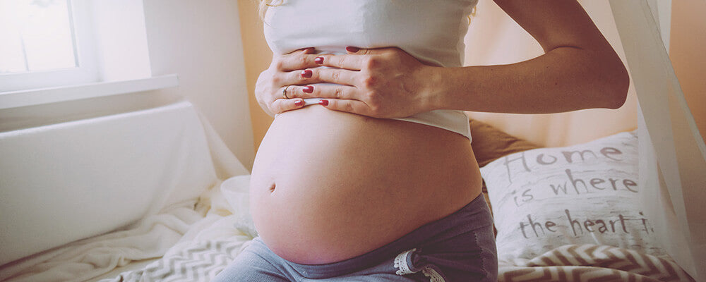 Torso de mujer embarazada con las manos en la barriga