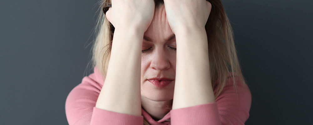 Mujer con las manos en la cabeza con expresión angustiada